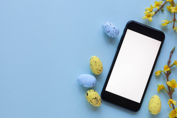 Happy easter background with tablet, yellow and blue eggs and spring flowers, top view.