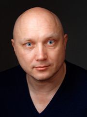 Portrait of a bald cheerful man on a black background