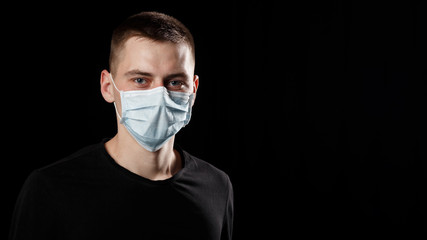 man with a procedure medical face mask from a coronavirus pandemic disease infection COVID-19 on black background