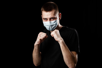 man with medical mask for coronavirus pandemic infection COVID-19 stands in a boxing stance on a...