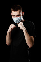 man with medical mask for coronavirus pandemic infection COVID-19 stands in a boxing stance on a...