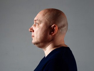 Portrait of a bald cheerful man in profile on a black background