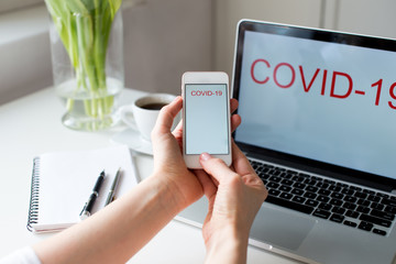 Quarantine and warning, outbreak alert notification on smartphone in woman hands and laptop devices. Stay at home advice to stop coronavirus COVID-19 spreading. Global pandemic Covid -19 prevention