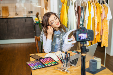 young beautiful caucasian woman show her palette for eyeshadow, new cosmetics for doing make-up. woman record video for subscribers, at home. blog, vlog concept