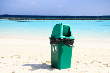 Obraz premium Green Plastic Flap Bin on Clean Sandy Tropical Beach after Recycling Waste