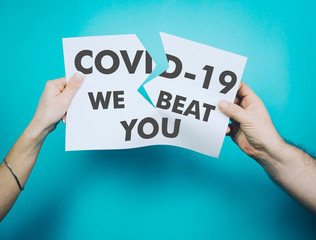 Female and male hands tear off a white sheet of paper with the word coronavirus. Covid-19 concept we are not afraid. We will beat you