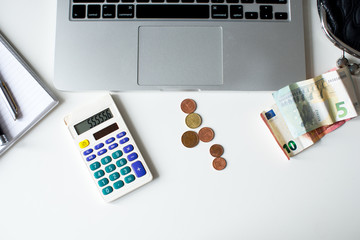 Business concept flat lay: laptop, money euro, calculator, Accounting concept.Analyzing finance report with calculator, Euro banknotes, calculator and Corona Virus, Economic impact Pandemics.