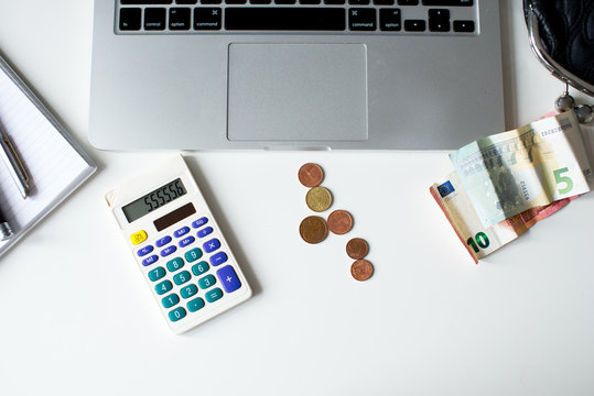 Business concept flat lay: laptop, money euro, calculator, Accounting concept.Analyzing finance report with calculator, Euro banknotes, calculator and Corona Virus, Economic impact Pandemics. 