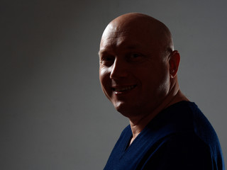 Portrait of a bald cheerful man in profile on a black background