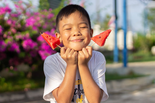 Portrait​ image​ of​ 5-6​ years​ old​ of​ child​.​ Happy​ Asian​ child​ boy​ eating​ and​ holding​ a​ watermelon​ in​ his​ hands.​ Summer​ season.​ Food​ and​ kid.