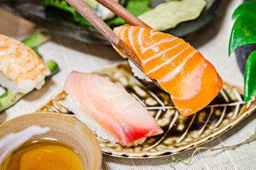 Salmon sashimi in chopsticks on sashimi set table.
