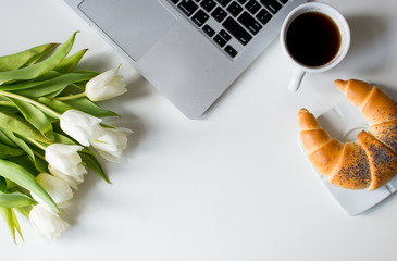 Coffee croissant  top view breakfast morning work office. Minimal styled flat lay isolated on white background. Feminine desk top view with white tulips, coffee, laptop. Copy space. White design