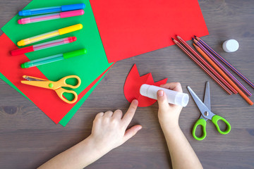 a child applies glue to a paper template of a red Tulip, children's handwork