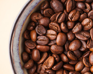 Coffee beans close-up on a light brown background. For screensavers, roasters and coffee sellers.
