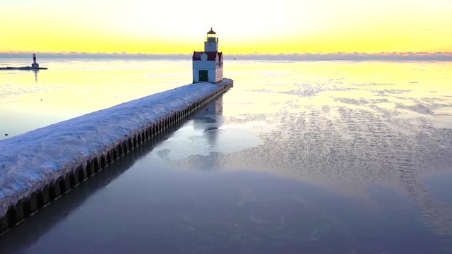 Iconic Lighthouse standing tall in frozen Lake Michigan harbor, Winter dawn.