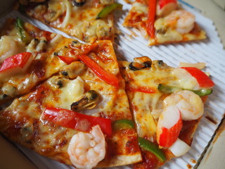 Sliced pizza with cheese, seafood and sausage, closeup