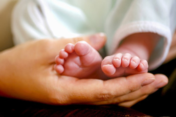 Pieds d'un bébé dans la main de sa mère