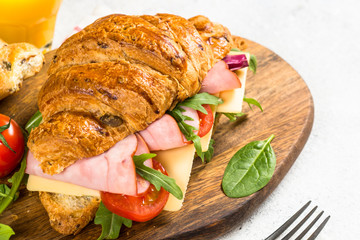 Croissant sandwich on white table.