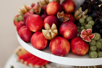 different kinds of fresh fruit on a tray on a banquet. fruit background with peaches, grapes and figs. selective focus