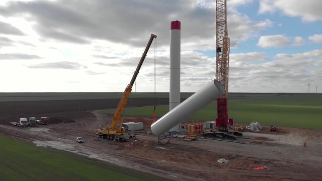 Building process of wind energy power tower mill, under construction. Installation tower, workers inside assembling the pillar of windmill. Green, clean, renewable energy. Aerial footage.