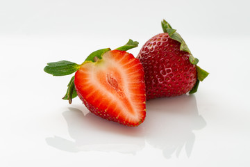Close up of fresh strawberries with leaves on a white background.