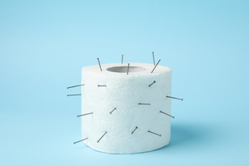 Toilet paper with nails on blue background, close up