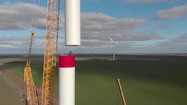 Building process of wind energy power tower mill, under construction. Installation tower, workers inside assembling the pillar of windmill. Green, clean, renewable energy. Aerial footage.