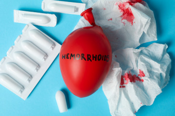 Balloon with inscription Hemorrhoids, candles and paper with blood on blue background