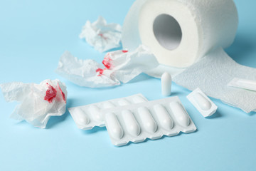 Toilet paper, candles and paper with blood on blue background, close up