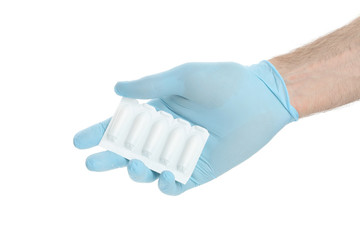 Hand in glove with anal or vaginal candles, isolated on white background