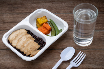 Take the chicken nicely in a plastic rice box on the wooden table.
