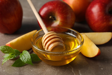 Apples and honey on gray background, close up