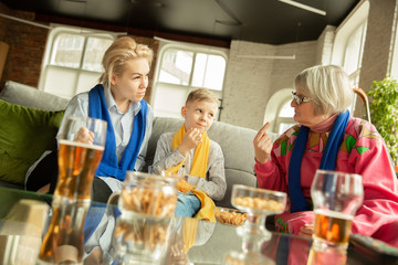 Excited family watching football, sport match at home. Grandma, mother and son cheering for national basketball, football, tennis, soccer, hockey team. Concept of emotions, support, cheering.