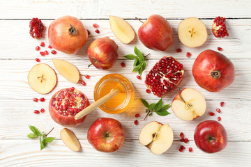 Apples, pomegranate and honey on wooden background, top view