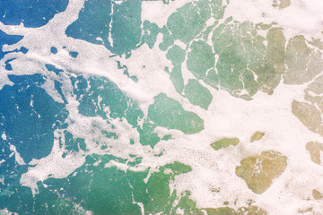 Top view texture waves, foaming and splashing in the ocean, sunny day.  Beautiful tropical sea in summer season image by aerial view. Abstract sea background. Ocean waves close-up.