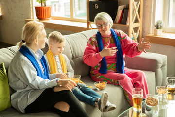 Excited family watching football, sport match at home. Grandma, mother and son cheering for national basketball, football, tennis, soccer, hockey team. Concept of emotions, support, cheering.