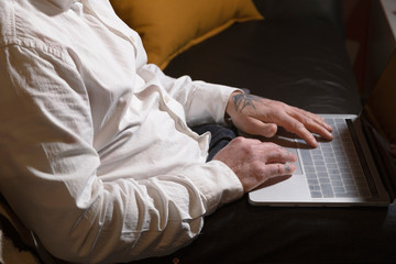 Closed shot of man working with laptop on sofa at home. Telework space on the sofa at home. Telework concept