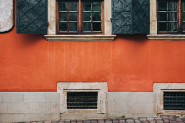 Open metal shutters on the old beautiful windows. Orange facade of the building of the Armenian courtyard in Lviv.