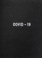 The words Covid-19 on black felt letter board