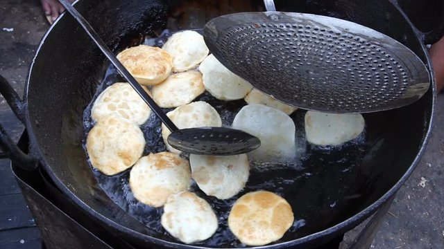 Many Kochuris are being fried in a frying pan. Kochuri, kachori of kachauri is a spicy snack, fried dumpling and a very popular street food in India.