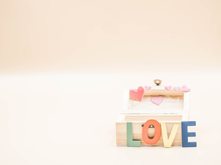 Selective focus at wooden multicolored alphabet word love and box with blurry pink pastel color heart sticker and background.