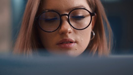 Fototapeta premium Portrait businesswoman reflection of light glasses focused works Internet laptop tablet female's eyes Close up woman in glasses use internet at night looking at display touchscreen computer monitor