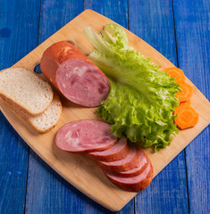 Slices of sausage, wheat bread and lettuce on a plate on the table close-up.