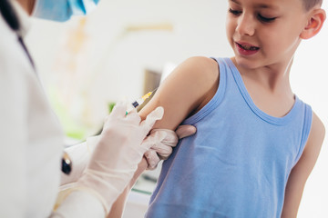 Obraz na płótnie Canvas Pediatrician makes vaccination to small boy. Female doctor vaccinating little boy.