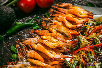  Gourmet appetizing prawns with salad and lemon on a metal tray on a wooden table, side view, horizontal