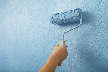 Hand with roller painting texture wall, close up