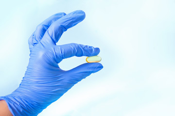 Medicine doctor in a blue latex gloves holding a capsule pill.
