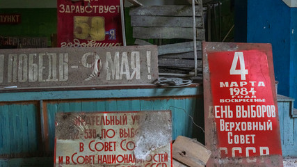 Empty room with a dirt covered signs in Russian language with posters of USSR slogans. Industrial catastrophe concept. Old USSR posters.