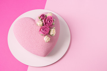 Modern  mousse cake .Heart shape  cake covered with pink chocolate velour and decoraited of pink roses.Pink background. Concept for Wedding , St. Valentine's Day, Mother's Day, Birthday Cake.