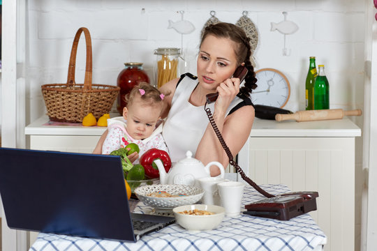 Mother with notebook and baby in kitchen. Isolation period, quarantine, social distancing. Remote education or remote work